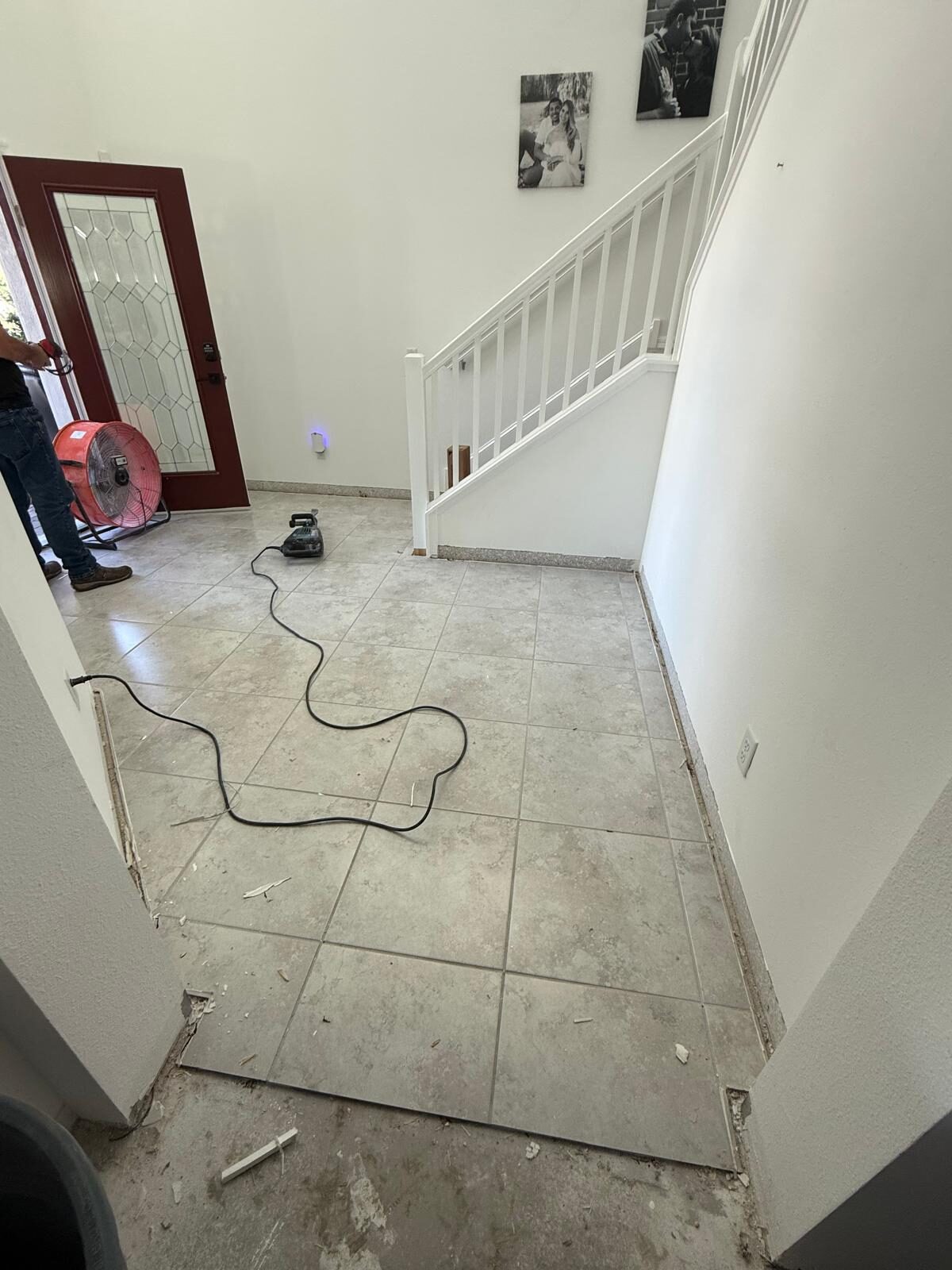 Tile flooring being removed near a staircase and front door