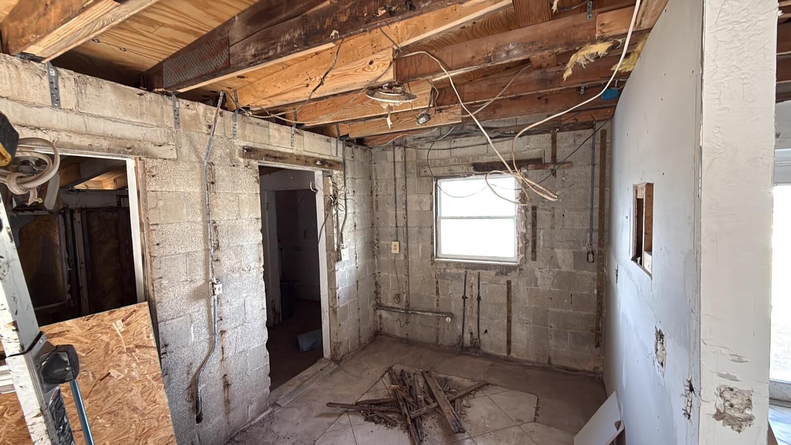 Interior of a house gutted to the studs, exposing concrete blocks and wiring