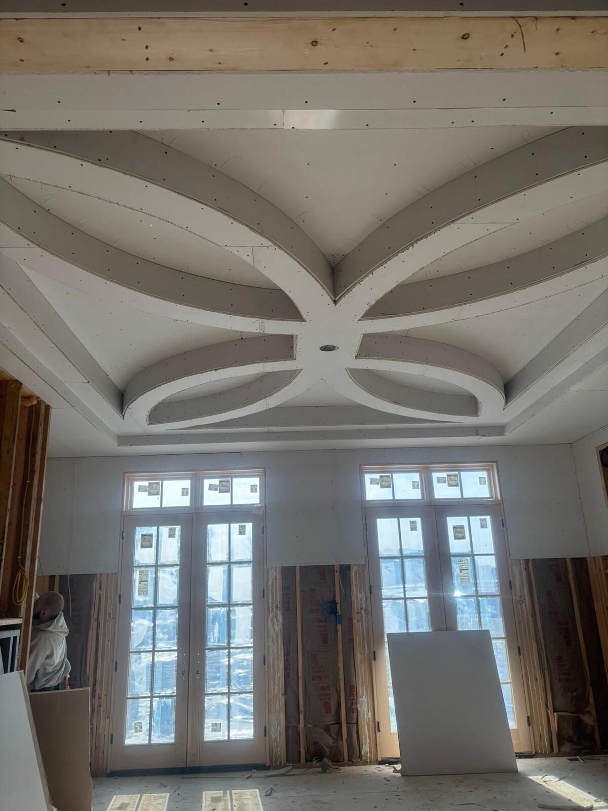 Custom drywall ceiling design in progress with natural light from large windows