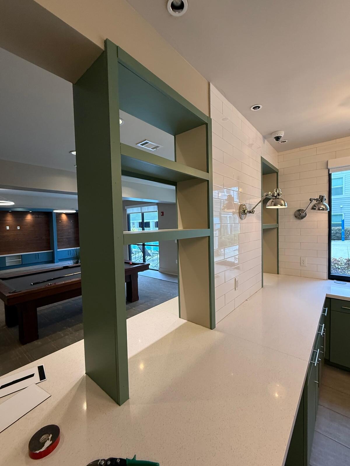 Modern kitchen with green cabinets and white subway tile in a commercial space
