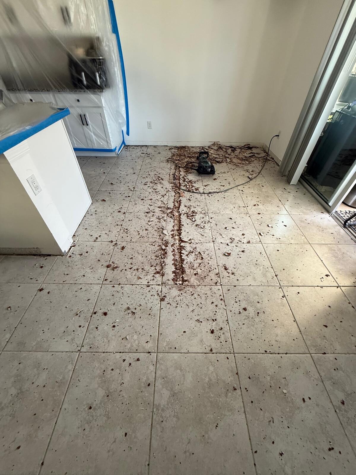 Existing tile flooring in kitchen being removed for new installation