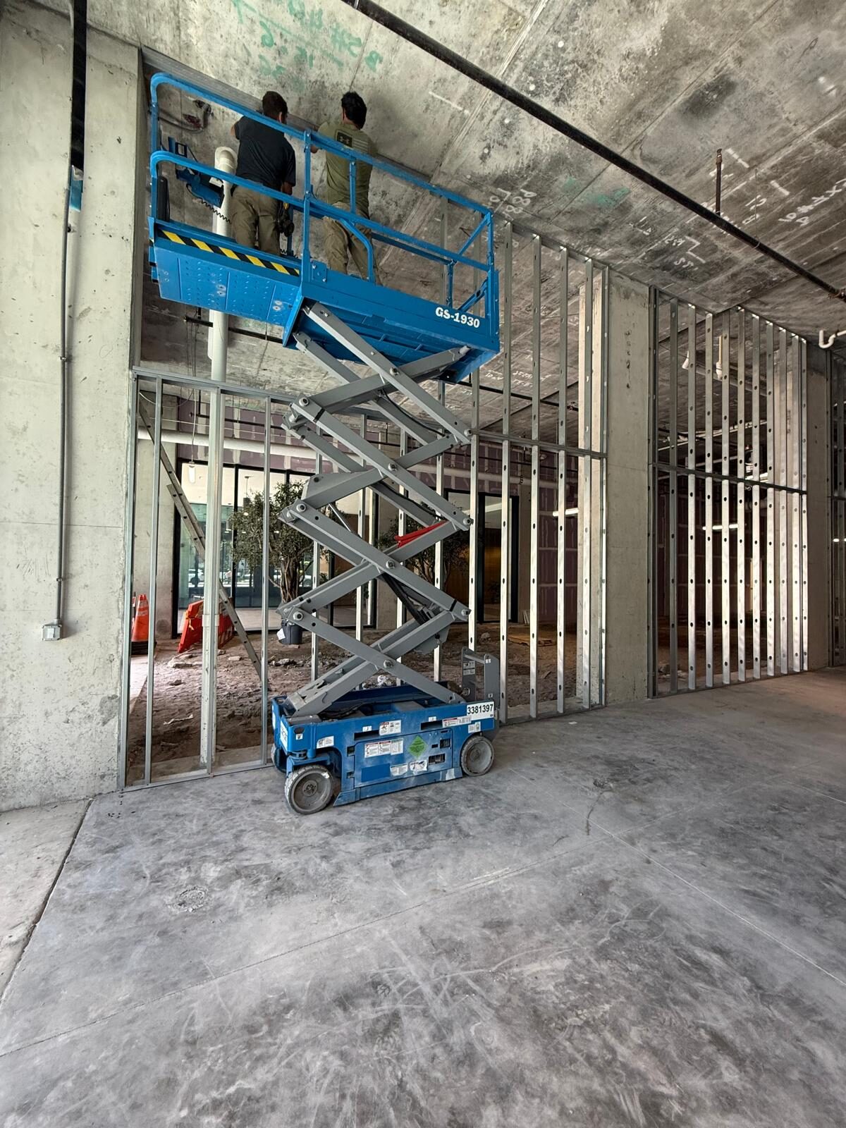 Workers on a scissor lift installing ceiling elements in a commercial space