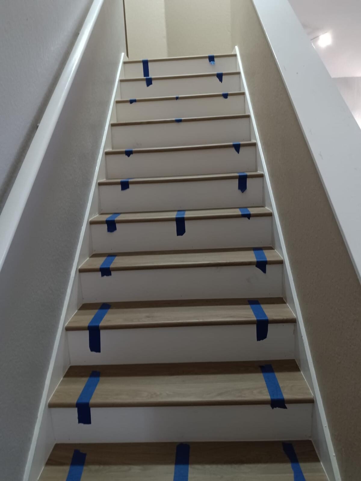 Staircase with wood-look tile treads protected by blue painter's tape