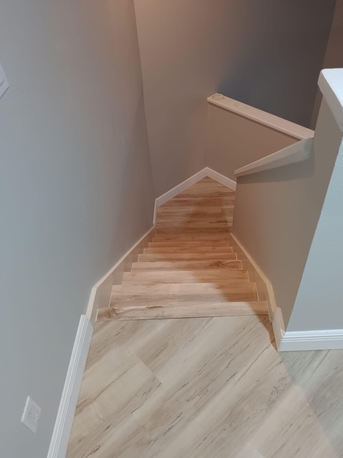 Finished staircase with wood-look tile and freshly painted grey walls