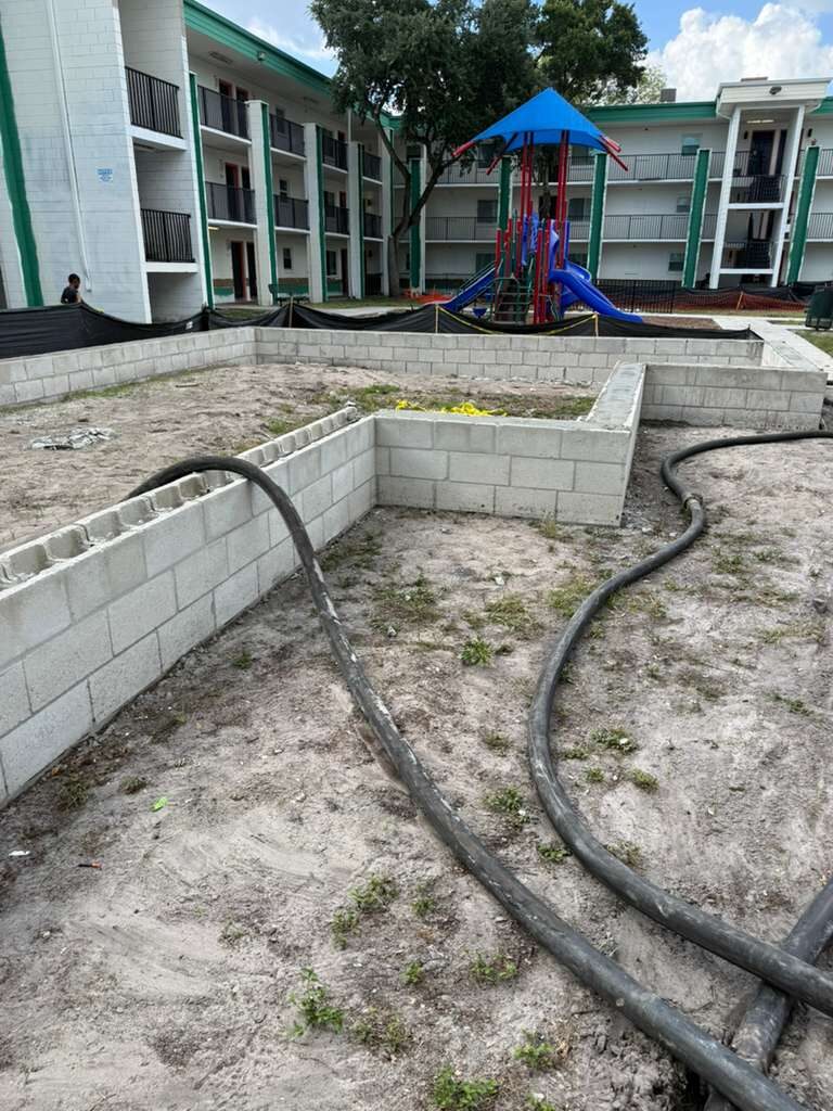 Building foundation work in progress outdoors near apartment complex and playground