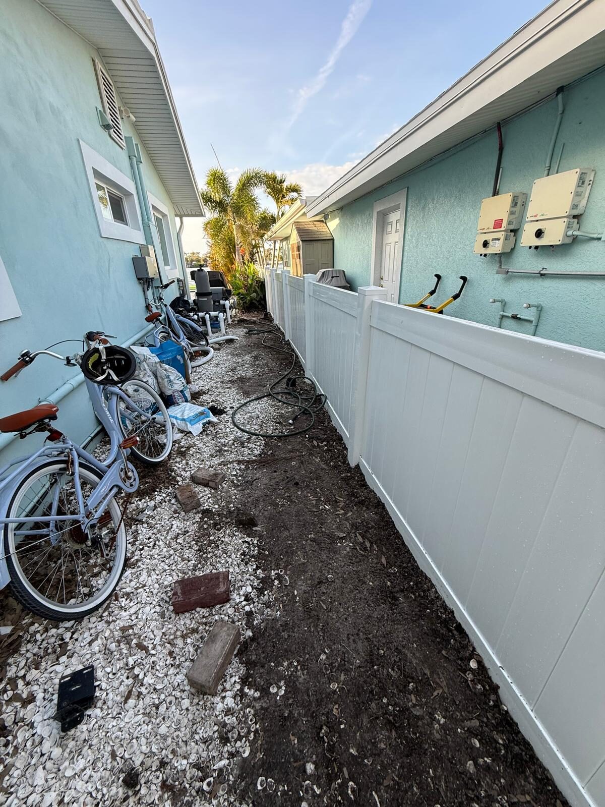 Installation of a white vinyl fence in a residential backyard setting with bikes