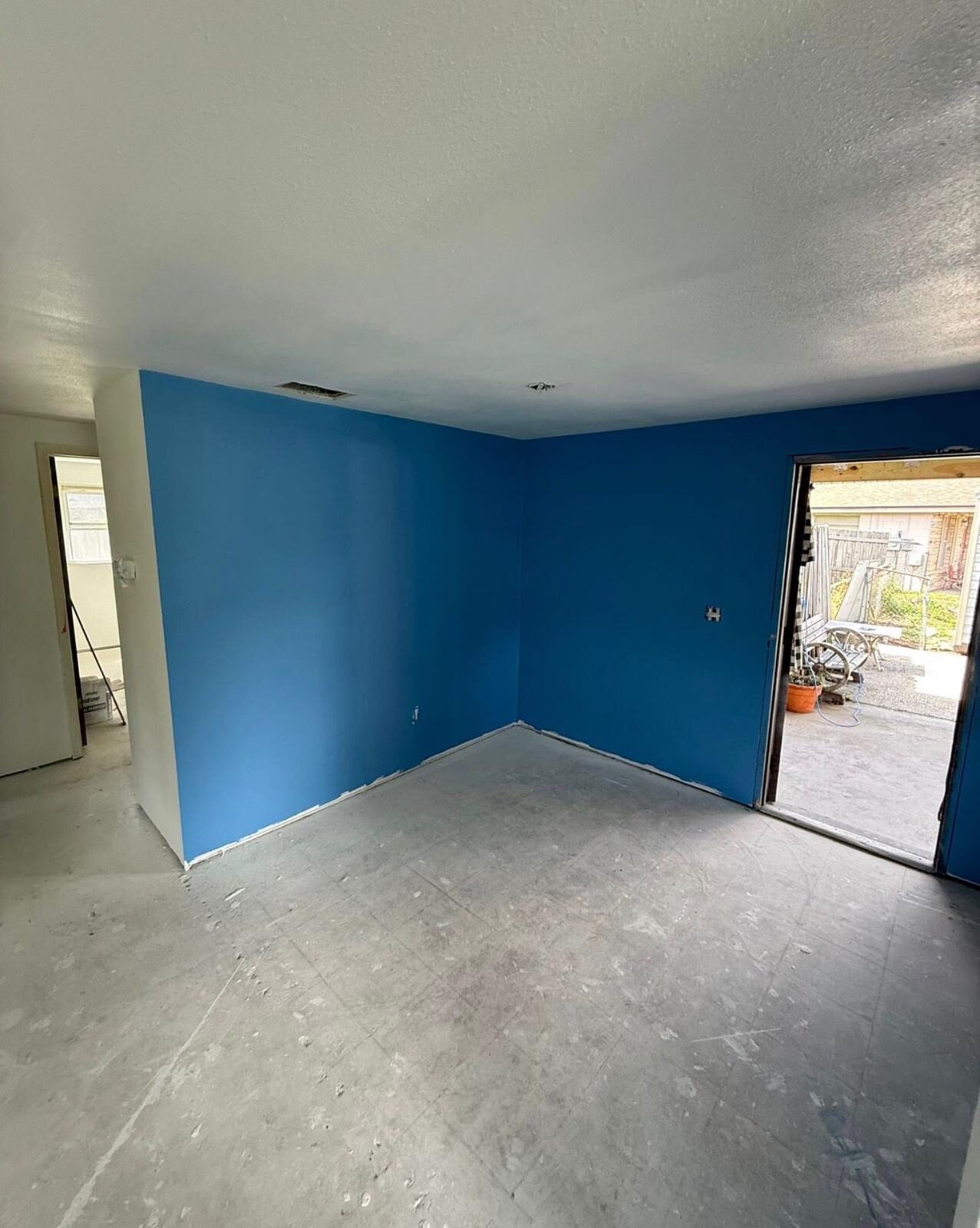 Room with a bold blue accent wall and un-floored concrete