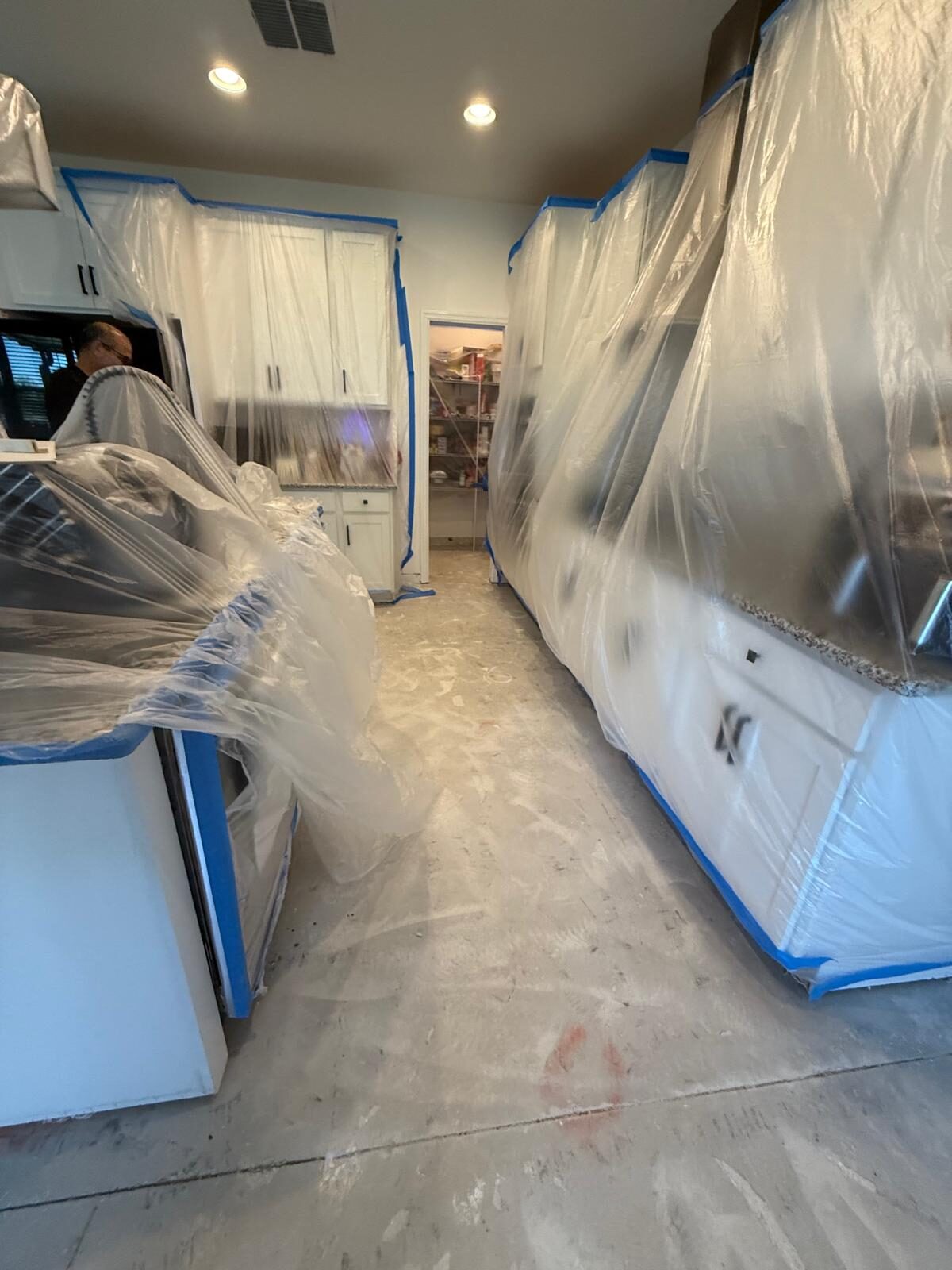 Kitchen cabinets and appliances covered with plastic during renovation work