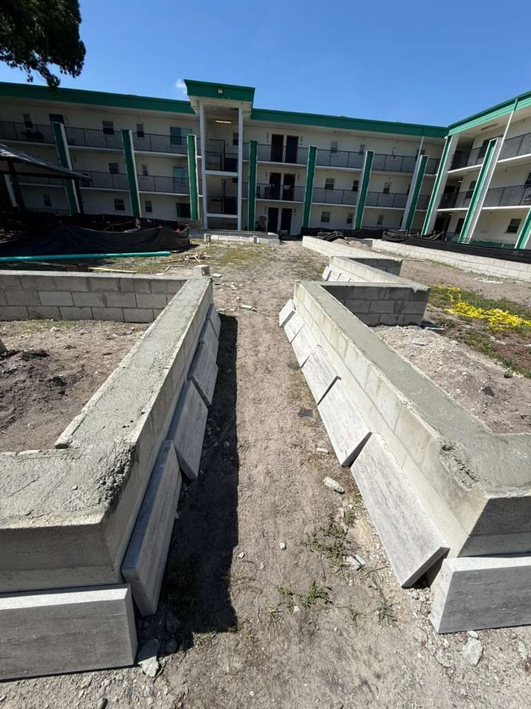 Concrete block planters or garden bed foundations in progress outside apartment building