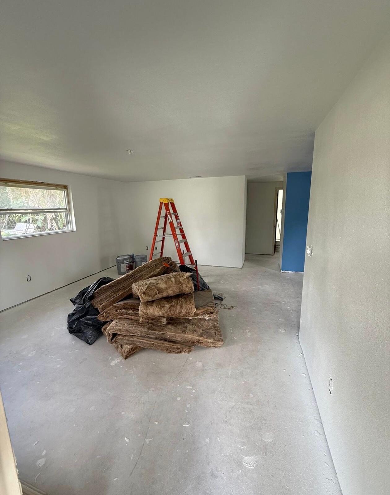 Insulation piles in a room with freshly painted white walls and a blue accent