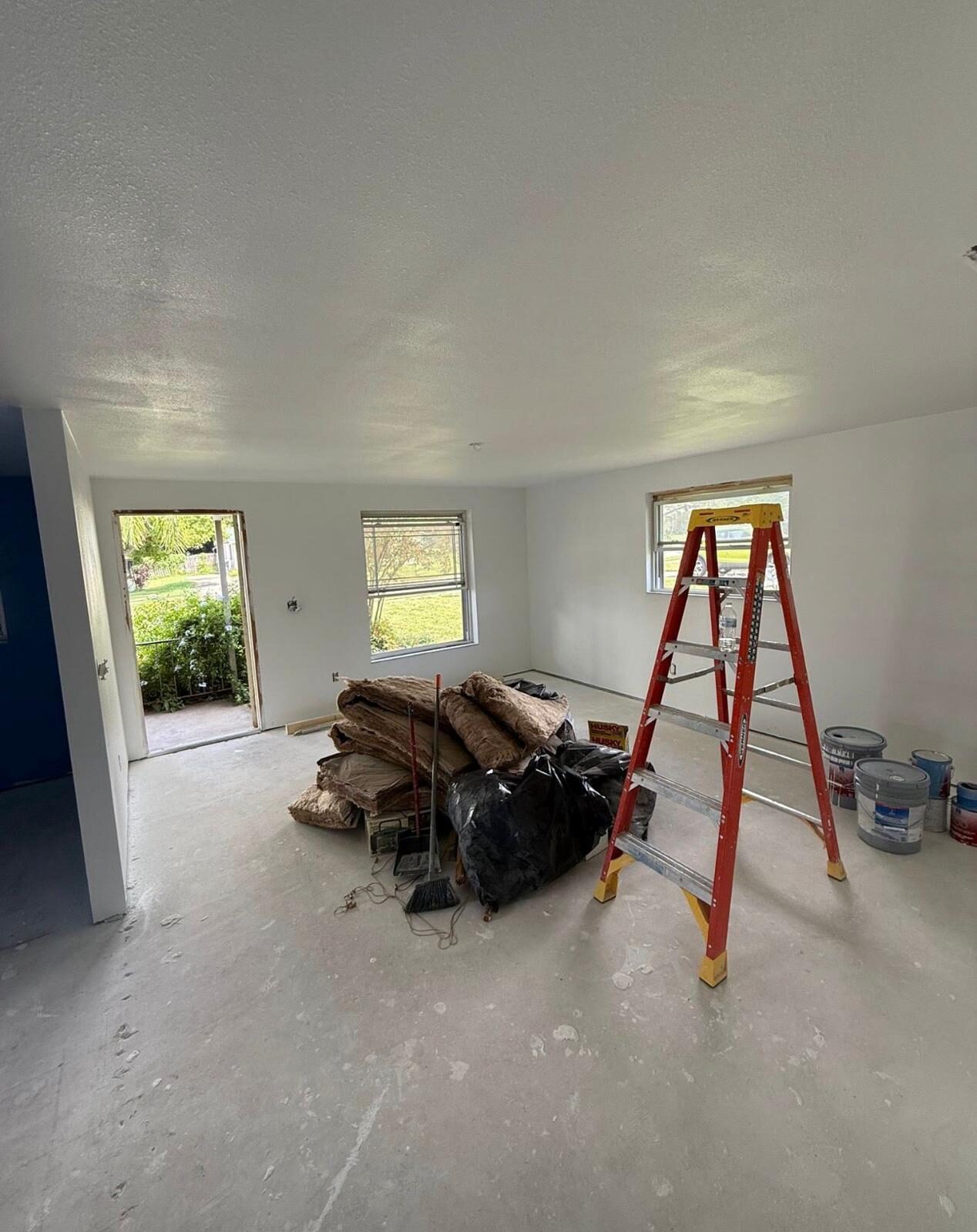 Interior room with freshly painted walls, insulation, and remodeling tools