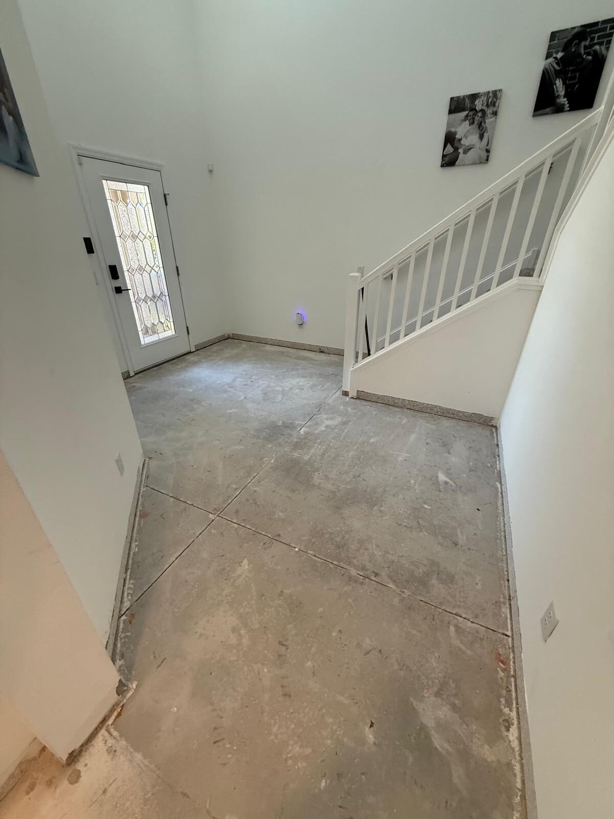 Entryway and staircase with concrete subfloor visible during renovation