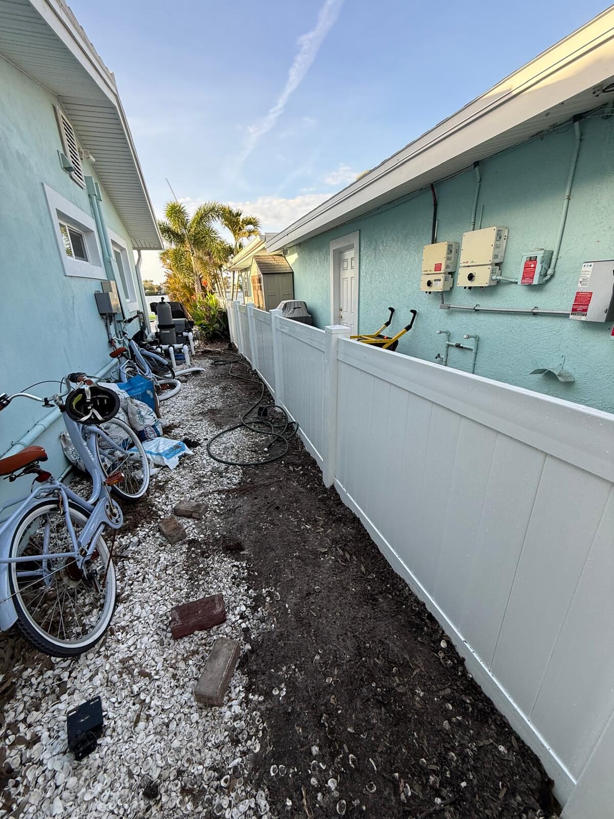 Newly installed white privacy fence next to a residential building and bicycles